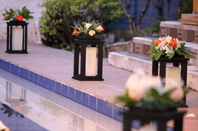 Lanterns with flowers next to a pool, creating a cozy atmosphere